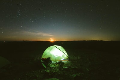 绿色露营帐篷里面有光在该领域的日落
